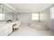 Spacious bathroom with a garden tub, white cabinets, and a vanity area with a stool at 2689 Spring Rock Ne Ct, Roswell, GA 30075