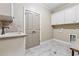 Well-lit laundry room featuring gray tile flooring, white cabinets and a utility sink at 3405 Camellia Ln, Suwanee, GA 30024