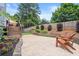 Relax on the backyard stone patio with wooden chairs surrounded by blooming flowers and lush greenery at 170 Shelli Ln, Roswell, GA 30075