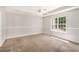 Carpeted primary bedroom featuring tray ceiling, ceiling fan, and a large window at 350 Dailey Mill Rd, Mcdonough, GA 30253