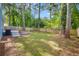 Large backyard featuring a fence line, green lawn, trees and a small patio area with steps at 6176 Hyde Park Ln, Lithonia, GA 30058