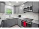 Modern kitchen boasts stainless steel appliances, gray cabinets, granite countertops, and a bright window at 6176 Hyde Park Ln, Lithonia, GA 30058