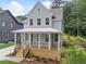 Well-manicured two-story house with a covered porch, gray siding, and lush greenery surrounding the property at 2214 Meador Ave Se, Atlanta, GA 30315