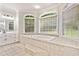 Bright bathroom featuring a soaking tub, tiled floor, large windows, and classic white cabinetry at 507 Wintergreen Way, Canton, GA 30115