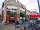 Exterior view of Mojo Pizza featuring its red accents, outdoor seating, and lush greenery at 1046 S Mcdonough St, Decatur, GA 30030