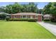 Charming brick home featuring a well-manicured front lawn, landscaped bushes, and a welcoming facade at 135 5Th Ave, Jonesboro, GA 30236