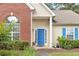 Bright blue front door framed by a brick facade and white columns and well maintained bushes at 1530 Brisbane Dr, Dacula, GA 30019