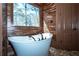 Modern freestanding bathtub with window view and wood look ceramic tiling at 297 Collegiate Dr, Powder Springs, GA 30127