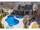 Backyard view with a sparkling pool and hot tub surrounded by a stone patio, perfect for outdoor entertainment at 297 Collegiate Dr, Powder Springs, GA 30127
