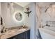 Modern bathroom with granite counters, stylish fixtures, a round mirror and a freestanding soaking tub at 3338 Peachtree Ne Rd # 1507, Atlanta, GA 30326