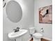 Minimalist bathroom features a pedestal sink, toilet, round mirror and modern fixtures, with simple decor at 4563 Sweetlake Court Sw, Mableton, GA 30127