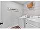 Bright laundry room with white washer and dryer, custom sign, and wire rack at 4563 Sweetlake Court Sw, Mableton, GA 30127