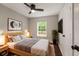 Cozy bedroom with wood accents, fan, large window, and minimalist decor with a bedside table and plant at 345 Adelle Se St, Atlanta, GA 30315