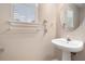 Neat powder room with a modern pedestal sink, a round mirror and natural lighting at 555 Sydney Crest Ln, Lawrenceville, GA 30046