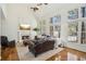 Bright living room with a fireplace, hardwood floors, and large windows offering a picturesque view at 7115 Doncaster Ct, Cumming, GA 30040