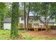 A spacious backyard with a large wooden deck attached to the white home, surrounded by lush greenery and mature trees at 2487 Highland Se Dr, Conyers, GA 30013