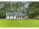 Charming white home with black accents, surrounded by a lush green lawn and mature trees at 2487 Highland Se Dr, Conyers, GA 30013