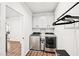 A tidy laundry room featuring a stainless steel washer and dryer set, with stylish white cabinets and wood-look flooring at 4189 Brookmont Way, Auburn, GA 30011
