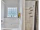 Bright bathroom featuring a tub and shower with tiled walls and a frosted glass block window for natural light at 4240 N Braves Cir, Douglasville, GA 30135