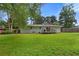 Large, grassy backyard featuring mature trees, and a cozy deck area attached to the house at 470 Pretty View Se Ln, Smyrna, GA 30082