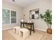 Neutral home office with a sleek black desk, cushioned ottomans, and bright natural light from a large window at 2000 Settindown Dr, Roswell, GA 30075