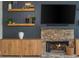Living room featuring a stone fireplace, floating shelves, and wood cabinets under a large television at 2000 Settindown Dr, Roswell, GA 30075