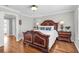 Bedroom featuring a decorative wood bed frame, hardwood floors, and bedside lamps on nightstands at 420 Heritage Park Nw Trce # 22, Kennesaw, GA 30144
