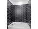 Close-up of tub and shower with black, hexagon tile surround at 461 Maypop Ln, Woodstock, GA 30188