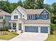 Charming two-story home featuring a three car garage and blue and white accents at 461 Maypop Ln, Woodstock, GA 30188