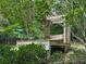 A covered wooden bench surrounded by lush greenery offers a serene outdoor seating space at 337 Theodore Cox Cir, Canton, GA 30114