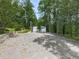 A single-story home featuring a white exterior, gravel driveway and surrounded by lush trees at 337 Theodore Cox Cir, Canton, GA 30114