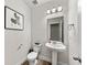 Clean, modern powder room with pedestal sink, decorative mirror, and neutral color scheme at 4065 Holland Grove Rd, Lawrenceville, GA 30044