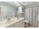 Bright bathroom featuring double vanity, white cabinets, and decorative shower curtain at 475 Chippenham Ct, Alpharetta, GA 30005