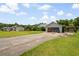 View of the home from the long driveway, showcasing the screened garage, lawn, and proximity to neighboring houses at 1587 Cronic Town Rd, Auburn, GA 30011
