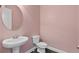 Charming half bath featuring a pedestal sink, toilet, and a round mirror on a pink wall at 1954 Summit Trace Circle Northwest, Atlanta, GA 30318
