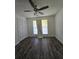 A clean and bright bedroom with wood floors, a ceiling fan, two windows, and a white painted door at 101 Royal Way, Mcdonough, GA 30252