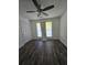 A clean and bright bedroom with wood floors, a ceiling fan, two windows, and a white painted door at 101 Royal Way, Mcdonough, GA 30252