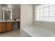 Bright bathroom with a white bathtub, wood vanity, and tiled floor at 5900 Union Woods Way, Union City, GA 30291