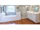 Bright bathroom with a tub under a window and a glass-door shower at 616 Piping Rock Pt, Lawrenceville, GA 30043