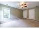 Large carpeted bedroom with closet doors and a window at 616 Piping Rock Pt, Lawrenceville, GA 30043
