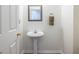 A well-lit powder room showcasing a pedestal sink, decorative mirror, and neutral wall color at 616 Piping Rock Pt, Lawrenceville, GA 30043