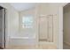 Bathroom with a bathtub, stand up shower, and travertine tile flooring at 773 Van Briggle Path, Sugar Hill, GA 30518