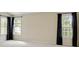 Spacious bedroom with neutral walls and carpet, plus 3 large windows with dark curtains at 773 Van Briggle Path, Sugar Hill, GA 30518