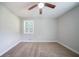 Neutral carpeted bedroom featuring a ceiling fan and a bright window with white trim at 10150 Puckett St, Covington, GA 30014