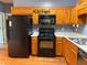 Kitchen featuring wooden cabinetry, black appliances, and laminate countertops at 169 Rachel Blvd, Temple, GA 30179