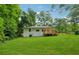 Wide view of back yard, back deck, grassy lawn, mature trees and home exterior at 4443 Flat Shoals Pkwy, Decatur, GA 30034