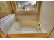 A soaking tub is surrounded by tile and has a window with a view at 4895 Sterling Close, Buford, GA 30518