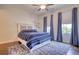 Well-lit bedroom with blue accents, hardwood flooring, ceiling fan, and window with natural light at 4895 Sterling Close, Buford, GA 30518