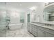 Bright bathroom showcasing a soaking tub under windows, double vanity, marble floors, and elegant lighting fixtures at 6175 Weatherly Dr, Sandy Springs, GA 30328