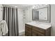 Well-lit bathroom with a rustic-style vanity, large mirror, and shower with gray curtain at 6175 Weatherly Dr, Sandy Springs, GA 30328
